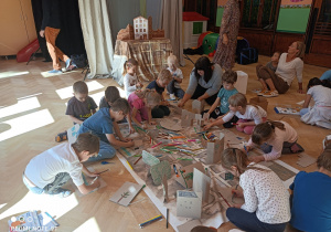 Na zdjęciu dzieci z grupy piątej wraz z Panią rysują mazakami na kartonach.